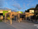 Devanture d'un bâtiment en bois avec pergola extérieure.